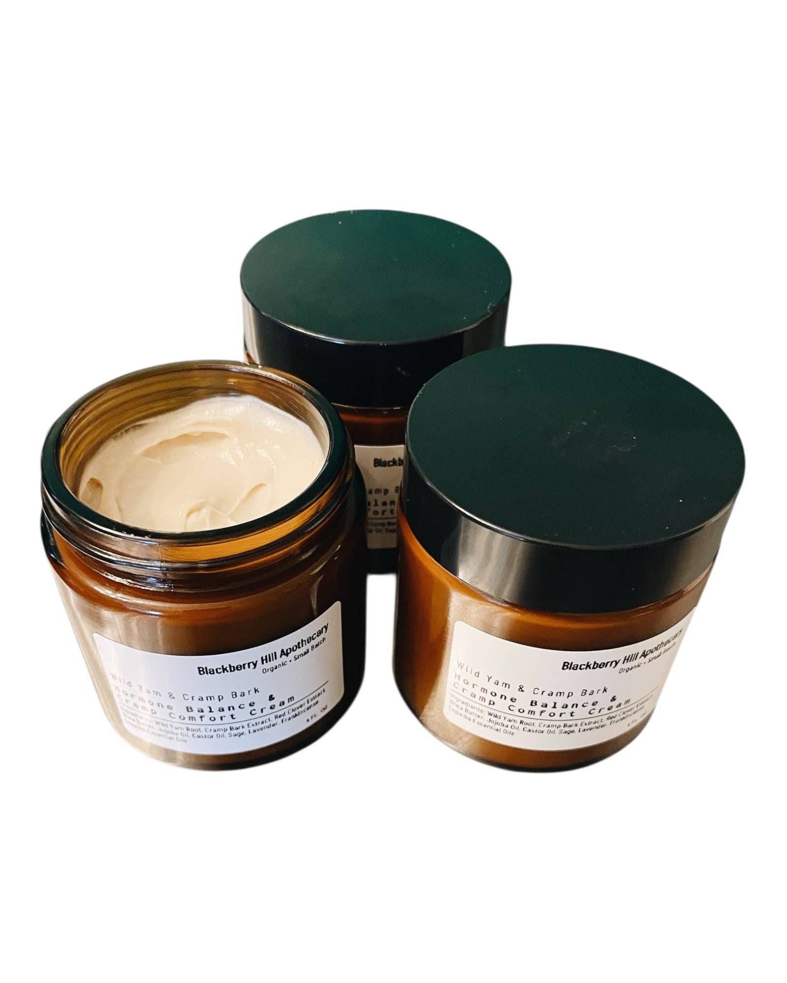 Three jars of cream with green lids on a white background
