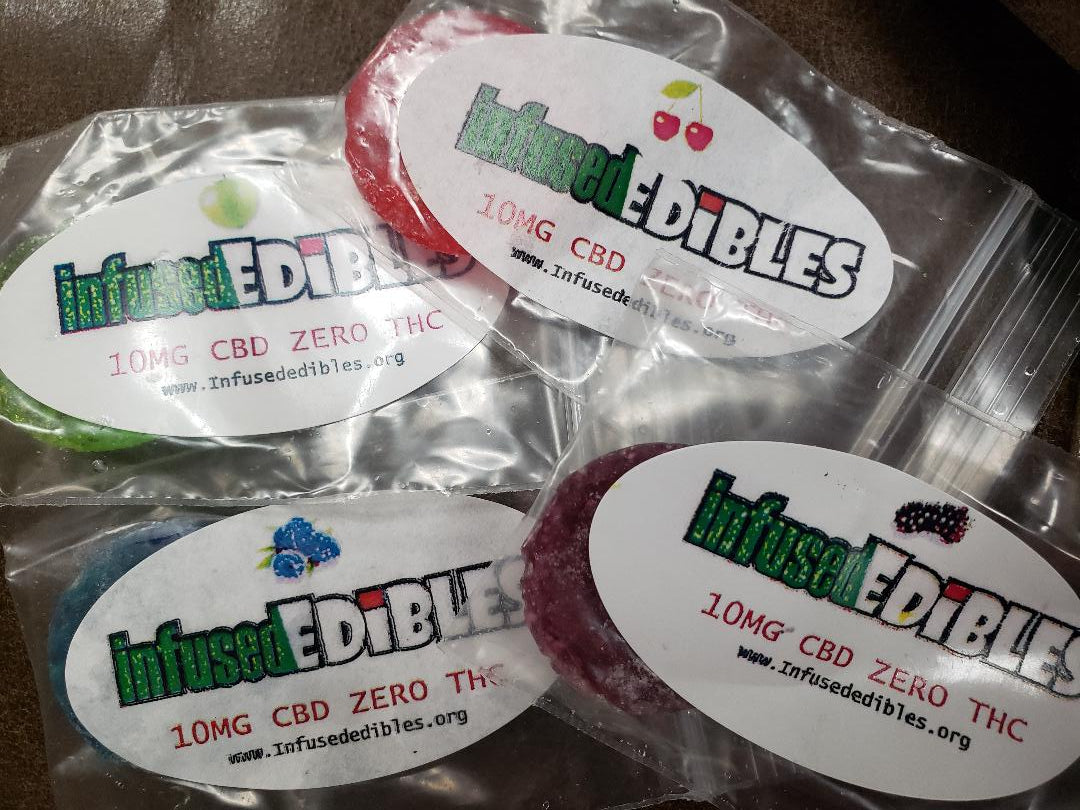 Individually wrapped hard candies in transparent packaging with various colorful labels, each labeled with a different flavor and the brand 'Infused Edibles'.