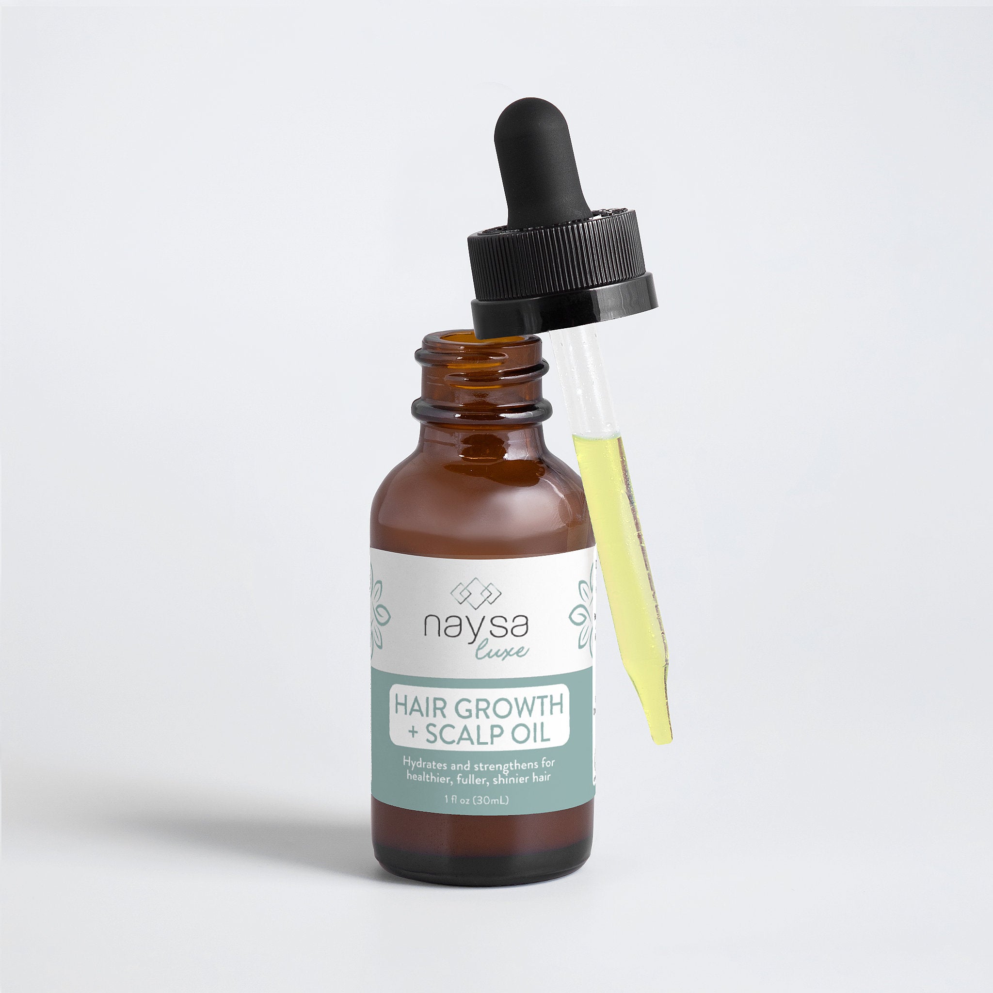 Bottle of naysa hair growth and scalp oil with dropper on a light gray background