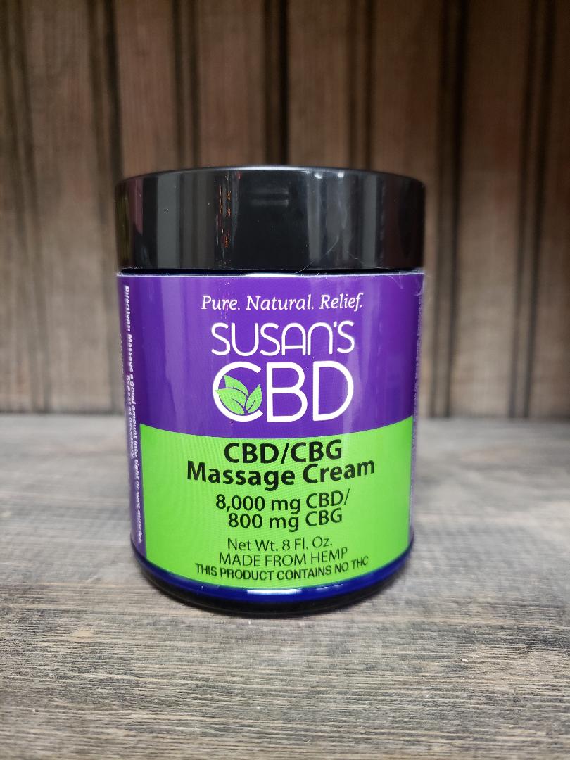 A container of Susan's Massage Cream with a label indicating 1000 mg CBD and 600 mg CBG. The container is green and purple with text detailing the product content.- Rich moisturizing pain relief formula
